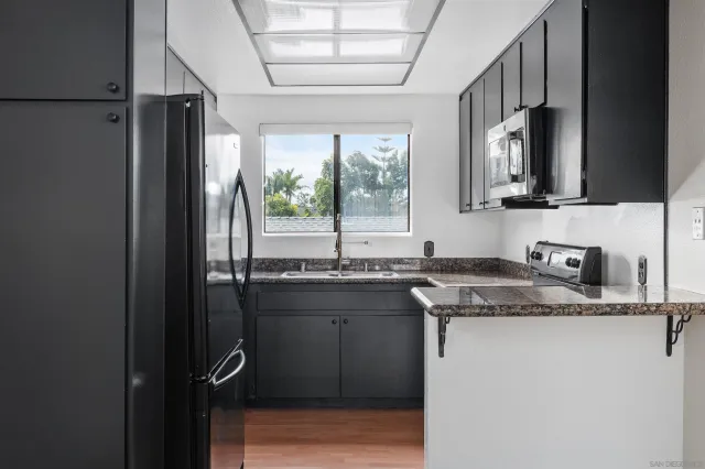 a kitchen with stainless steel appliances granite countertop a sink stove and refrigerator