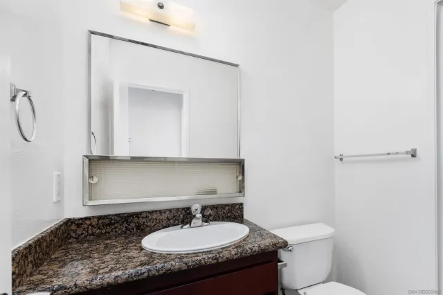 a bathroom with a granite countertop sink and a mirror