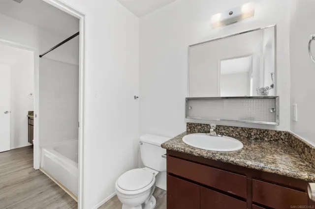 a bathroom with a granite countertop sink toilet and mirror