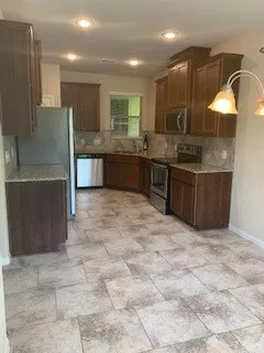a large kitchen with kitchen island a sink stainless steel appliances and a counter space