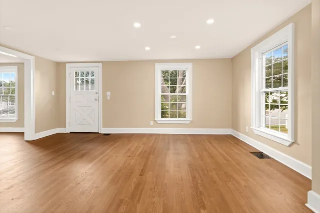 a view of an empty room with wooden floor and windows