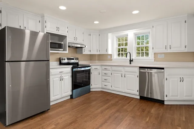a kitchen with white cabinets stainless steel appliances and wooden floors