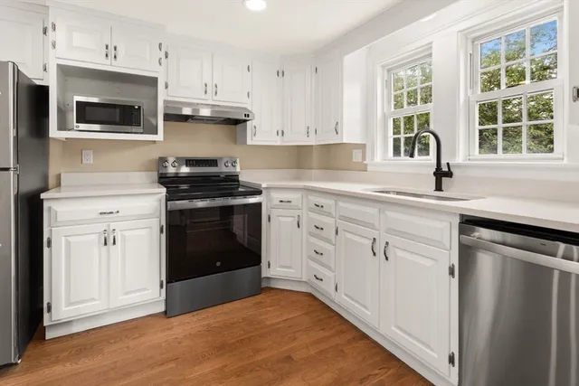 a kitchen with cabinets stainless steel appliances a sink and a window