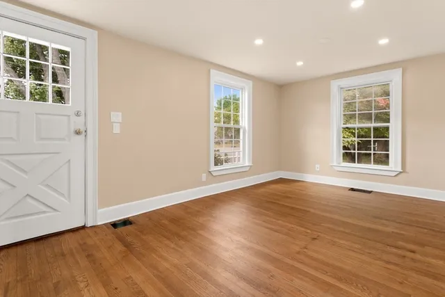 an empty room with wooden floor and windows