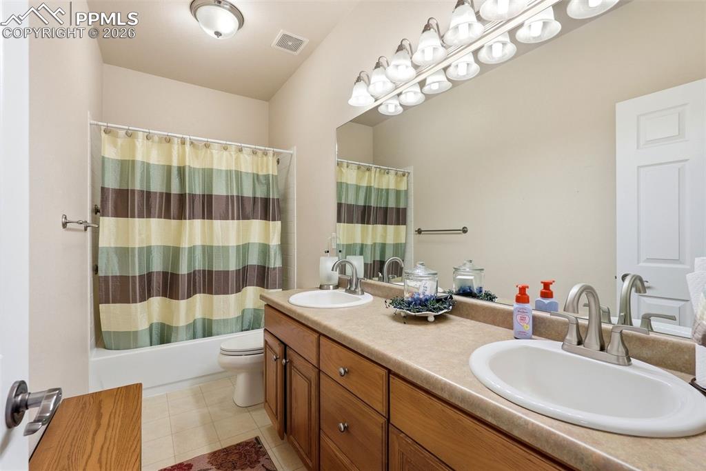 16261 Hobson Place Monument, CO 80132 - Photo 29 of 50 a bathroom with a double vanity sink a toilet a mirror and shower