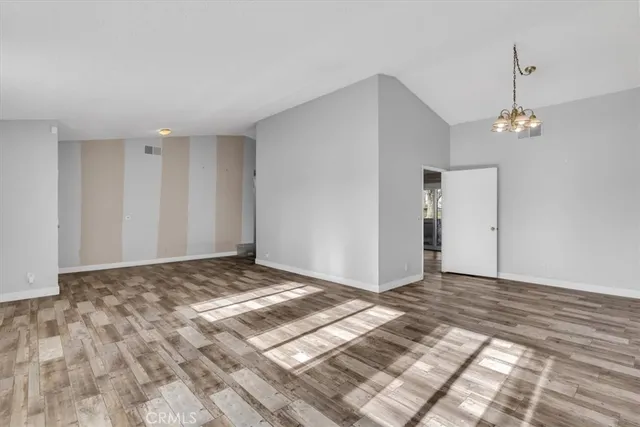 a view of a big room with a chandelier fan and wooden floor
