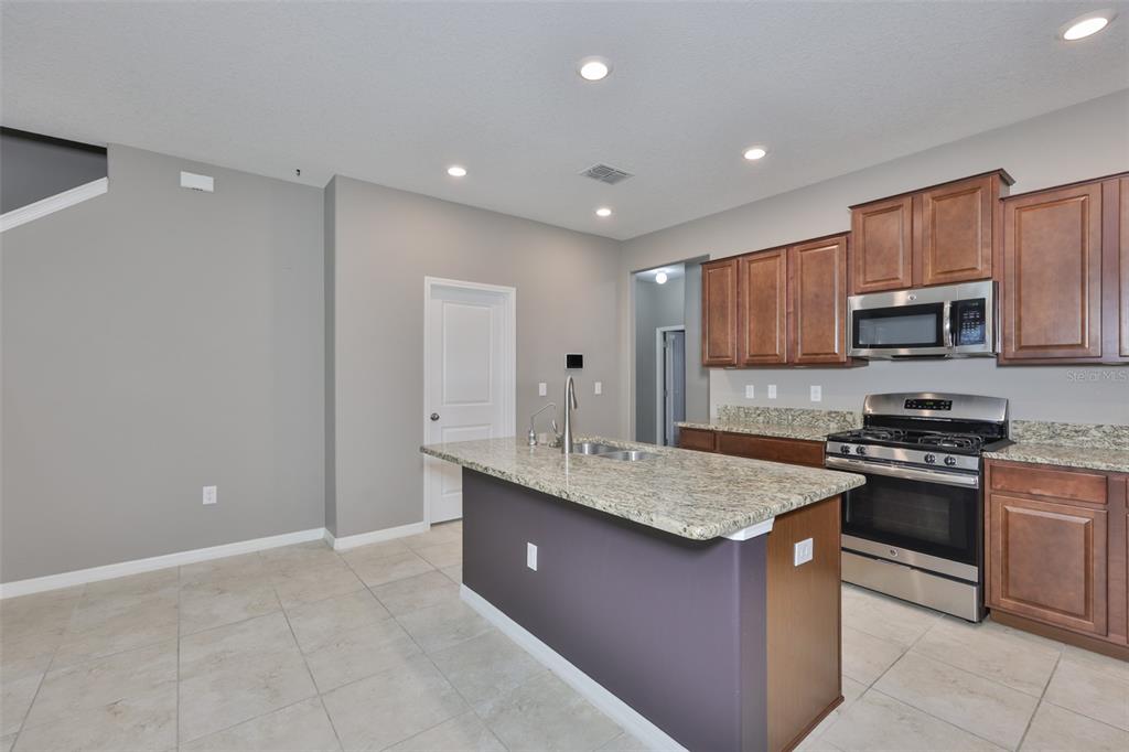 6330 Lantern View Place Apollo Beach, FL 33572 - Photo 11 of 64 a kitchen with stainless steel appliances granite countertop a sink stove and refrigerator