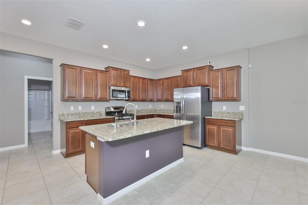 6330 Lantern View Place Apollo Beach, FL 33572 - Photo 7 of 64 a kitchen with stainless steel appliances granite countertop a sink stove and refrigerator