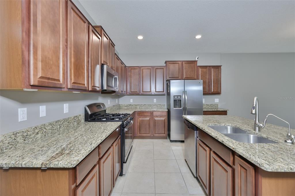 6330 Lantern View Place Apollo Beach, FL 33572 - Photo 9 of 64 a kitchen with kitchen island granite countertop a sink counter top space a stove and cabinets