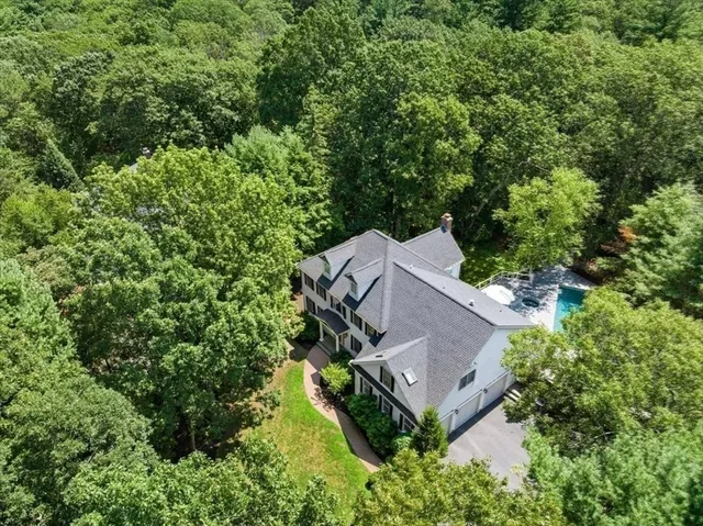 an aerial view of a house with a yard and trees all around