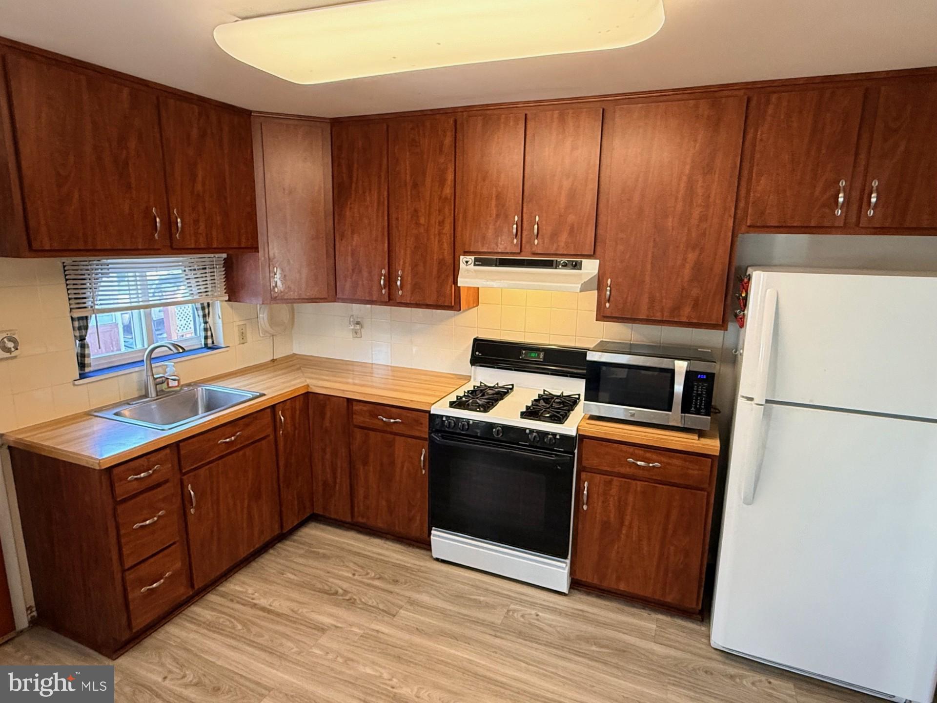 1446 Fitzwatertown Road Willow Grove, PA 19090 - Photo 6 of 19 a kitchen with wooden cabinets and white appliances