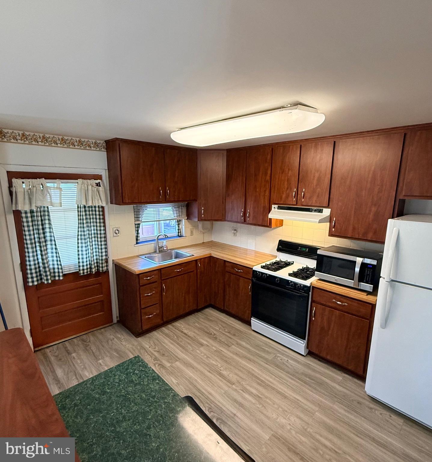 1446 Fitzwatertown Road Willow Grove, PA 19090 - Photo 7 of 19 a kitchen with granite countertop a stove top oven a sink dishwasher and a refrigerator with wooden floor