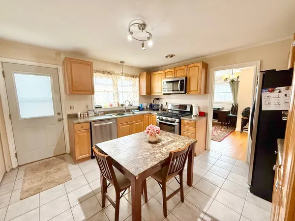 a kitchen with stainless steel appliances granite countertop a stove top oven a sink a dining table and chairs