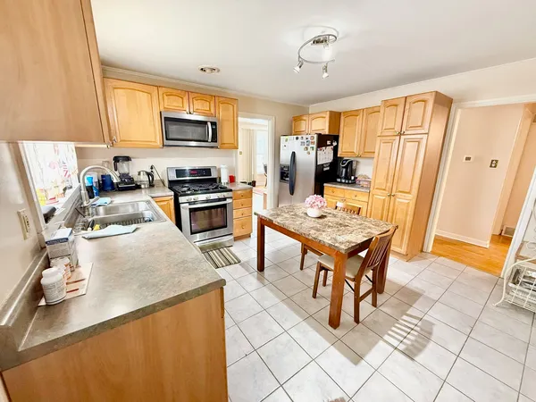 a kitchen with a refrigerator a stove top oven a sink dishwasher and wooden cabinets