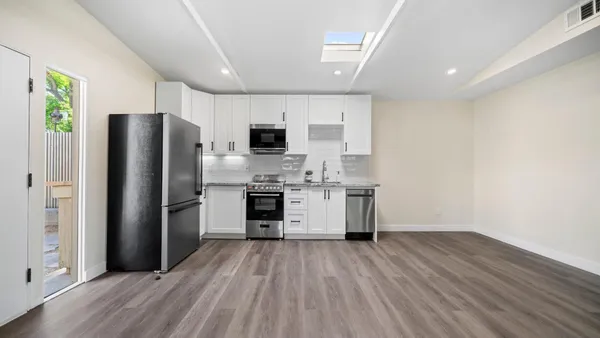 a kitchen with stainless steel appliances a stove a sink and white cabinets