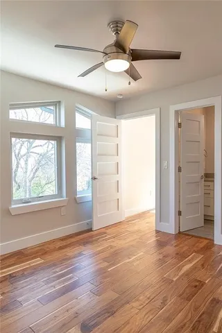 an empty room with wooden floor cabinet and windows