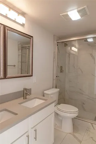 a bathroom with a granite countertop sink toilet a mirror and shower