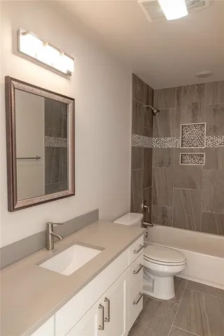 a bathroom with a granite countertop sink toilet a mirror and shower