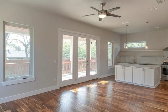 a open kitchen with granite countertop a stove top oven a sink and white cabinets with wooden floor