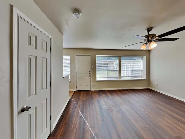 a view of an empty room with wooden floor and a window