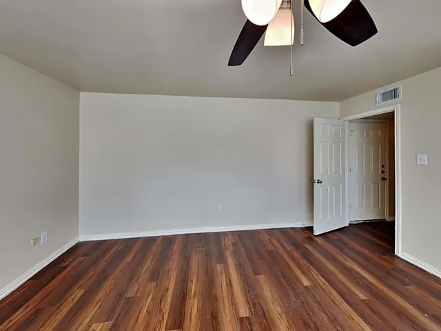 an empty room with windows and fan