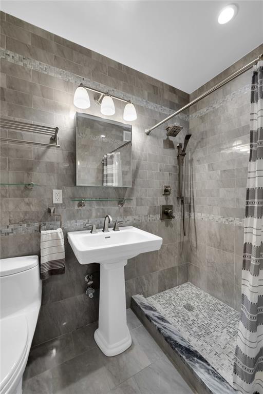 9201 Shore Road, Unit C701 Brooklyn, NY 11209 - Photo 6 of 9 a bathroom with a sink a toilet and shower