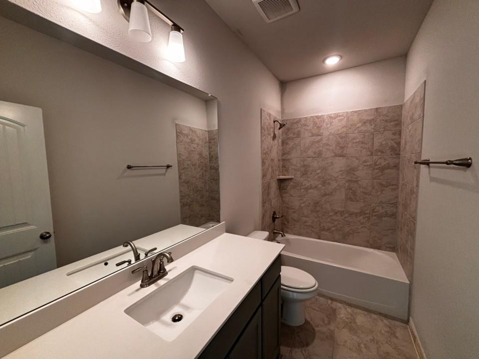 149 Big Sky Road Decatur, TX 76234 - Photo 10 of 11 Bathroom featuring a single vanity with an integrated sink, broad wall mirror, overhead lighting, and a tub with tiled surround