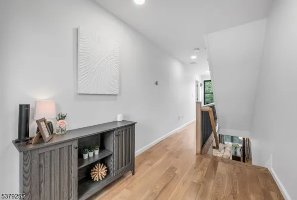 a hallway with a view of living room with wooden floor