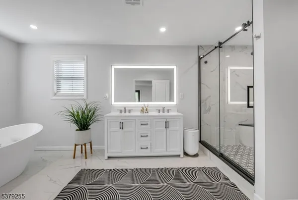 a spacious bathroom with a double vanity sink a mirror and a bathtub