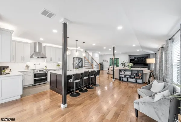 a living room with furniture and kitchen view with wooden floor