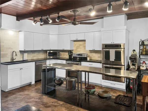 a kitchen with stainless steel appliances granite countertop a refrigerator a stove a sink dishwasher a microwave oven with cabinets and wooden floor