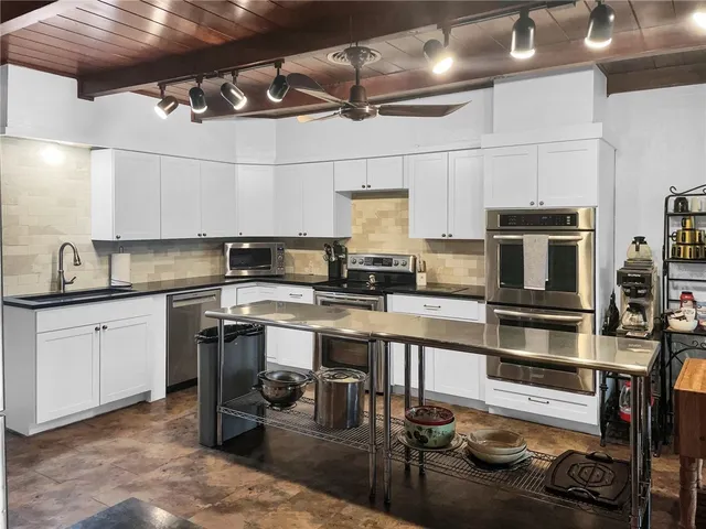 a kitchen with stainless steel appliances granite countertop a refrigerator a stove a sink dishwasher a microwave oven with cabinets and wooden floor