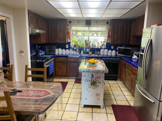 a kitchen with stainless steel appliances granite countertop a refrigerator a stove and a sink