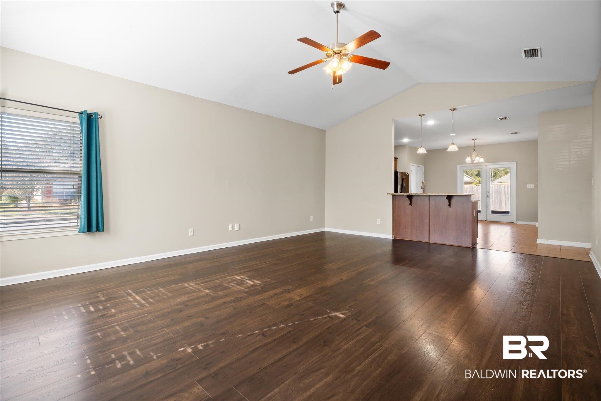 10251 Fionn Loop Daphne, AL 36526 - Photo 3 of 28 Unfurnished living room featuring french doors, ceiling fan with notable chandelier, dark wood-type flooring, and vaulted ceiling