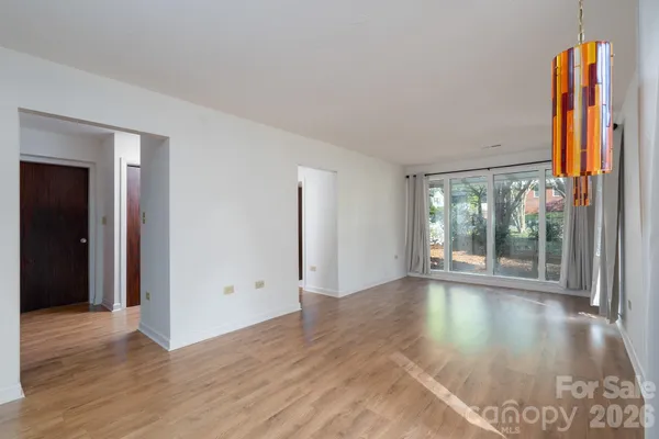 a view of a hallway with wooden floor and a bathroom