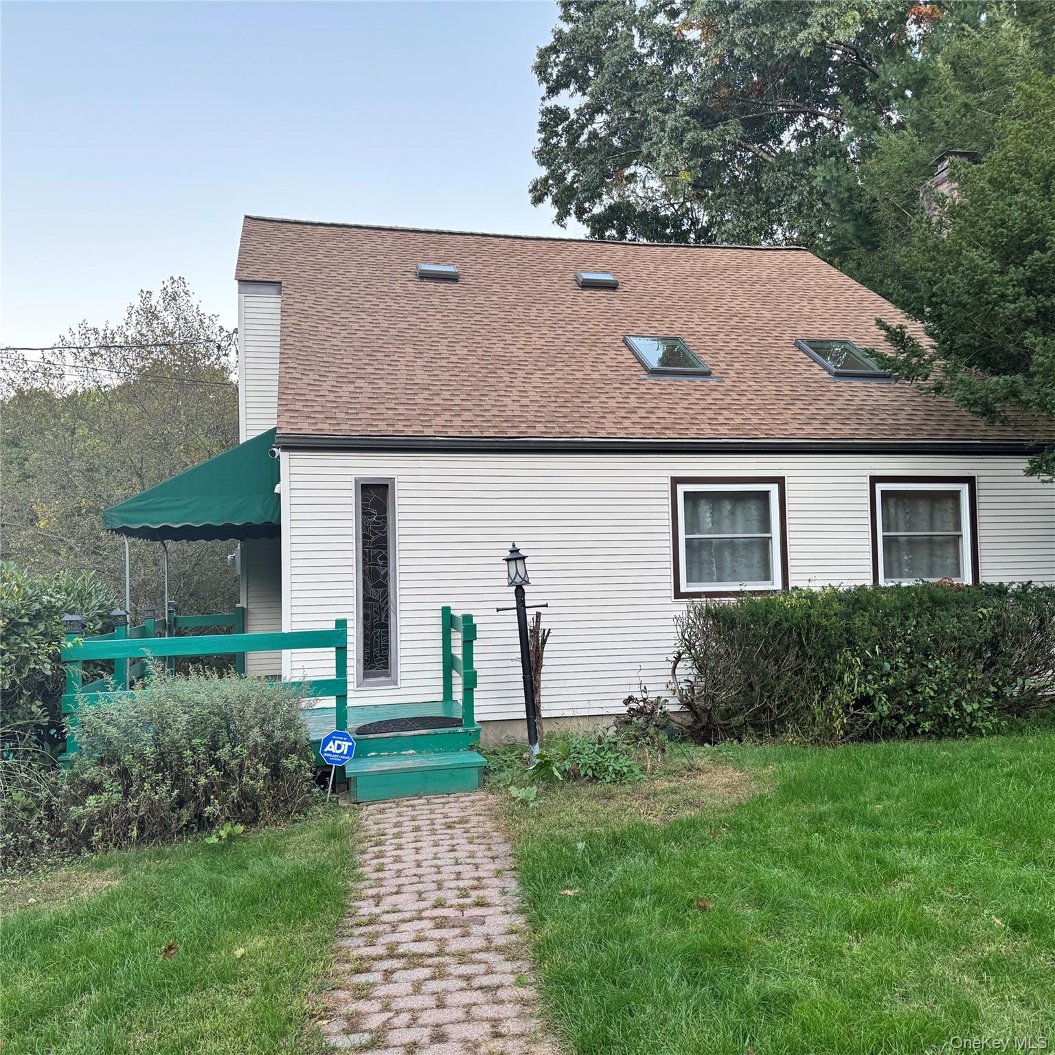 67 Steele Road New Windsor, NY 12553 - Photo 32 of 34 Light-colored siding exterior with a brown shingle roof featuring multiple skylights