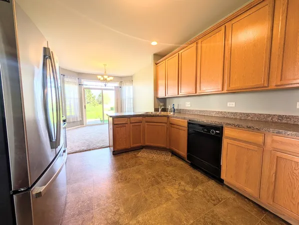 a kitchen with stainless steel appliances granite countertop a refrigerator a sink dishwasher and wooden cabinets with a granite countertops