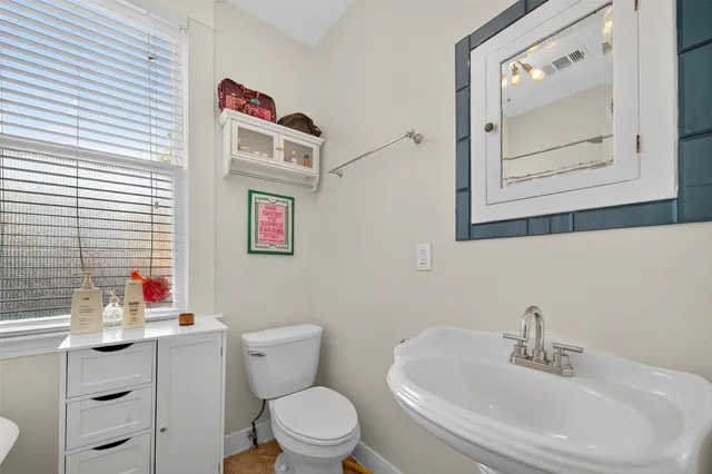 a bathroom with a toilet sink vanity and mirror