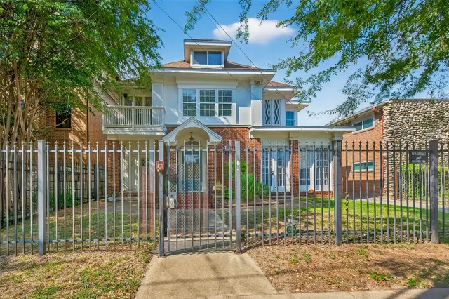 a view of a brick house with a large trees and plants