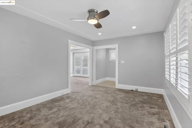 an empty room with windows and chandelier fan