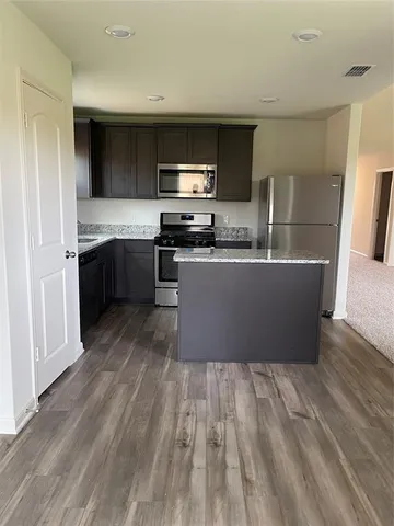 a large kitchen with stainless steel appliances granite countertop a lot of cabinets and wooden floor