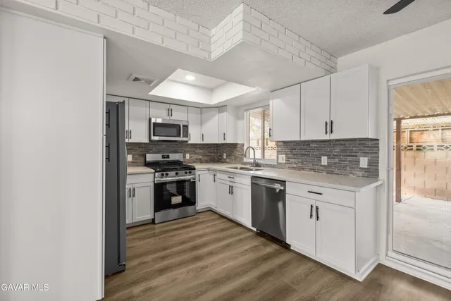 a kitchen with granite countertop white cabinets and stainless steel appliances