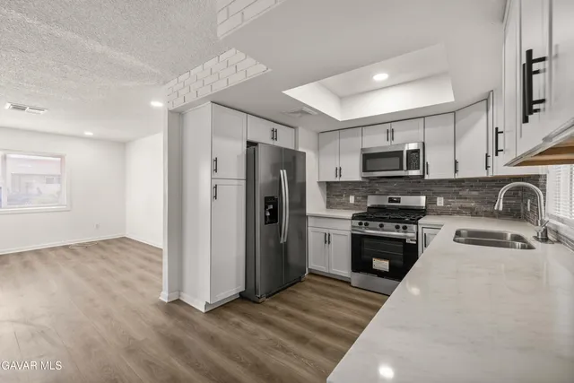 a kitchen with granite countertop a refrigerator stove and microwave
