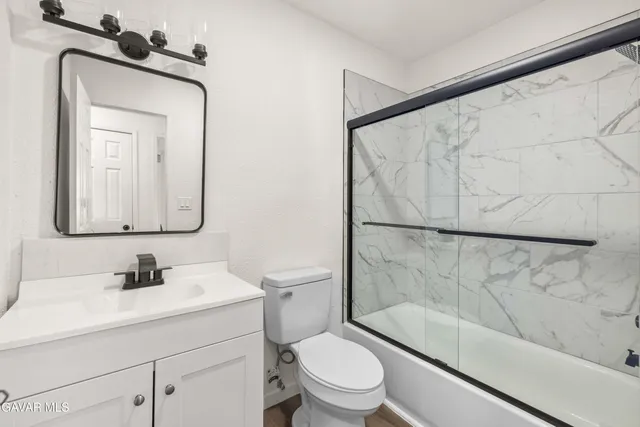 a bathroom with a toilet a sink a mirror a bathtub and shower