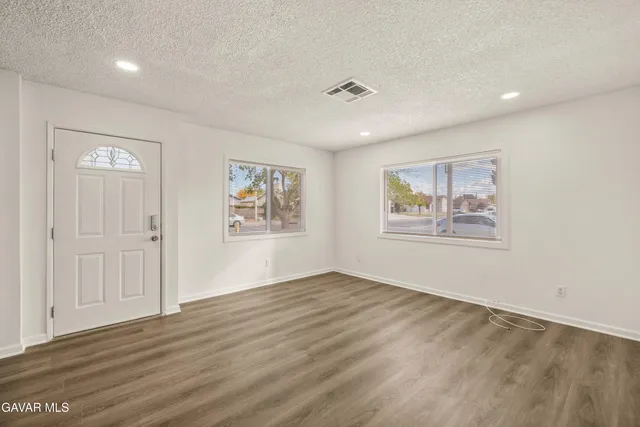 a view of an empty room with wooden floor and window