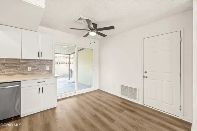 a kitchen with white cabinets and wooden floor