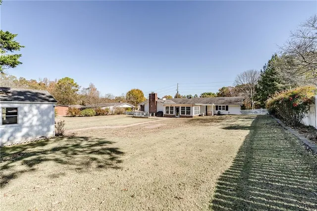 a view of swimming pool with lawn chairs and large trees