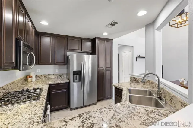 a kitchen with kitchen island granite countertop a refrigerator and a sink