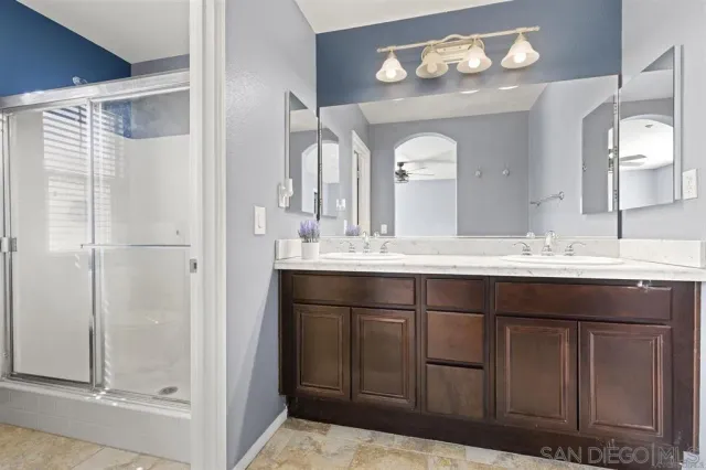 a bathroom with a granite countertop sink a large mirror and a shower