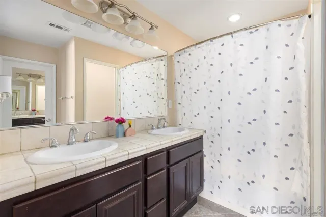 a bathroom with a granite countertop sink a mirror and shower